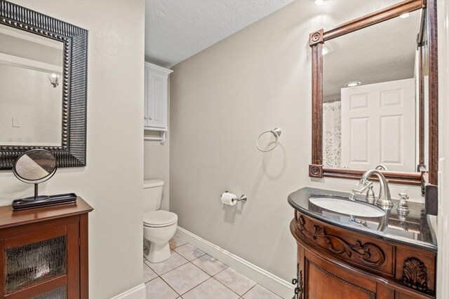 full bath with a textured ceiling, toilet, vanity, baseboards, and tile patterned floors