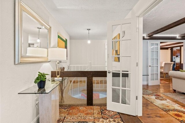 interior space featuring hardwood / wood-style floors, a textured ceiling, and french doors