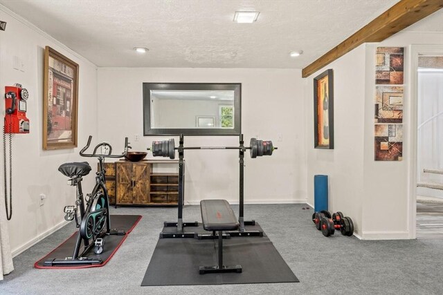 exercise area featuring a textured ceiling, carpet floors, and baseboards