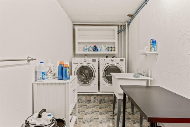 clothes washing area featuring laundry area, separate washer and dryer, and a textured wall