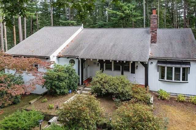 ranch-style house with a shingled roof and a chimney