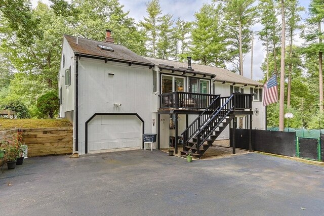 view of front of home with aphalt driveway, fence, a chimney, and stairs