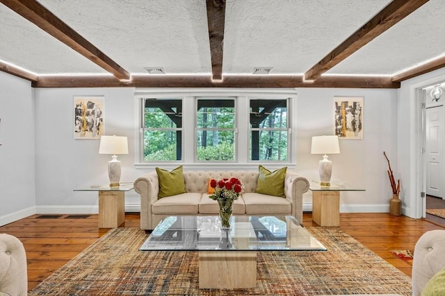 living area with a wealth of natural light, beam ceiling, a textured ceiling, and hardwood / wood-style flooring