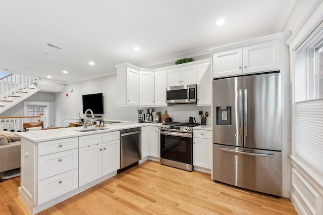 kitchen featuring appliances with stainless steel finishes, kitchen peninsula, sink, and white cabinets