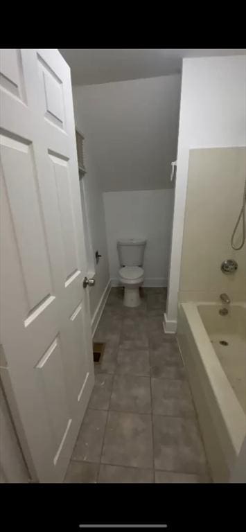 bathroom with tile patterned flooring, toilet, and washtub / shower combination