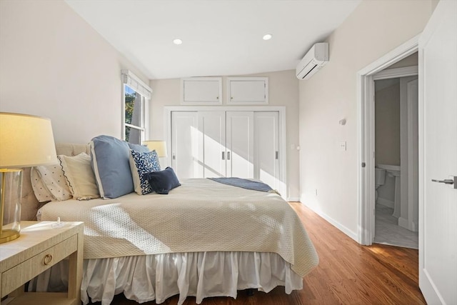 bedroom featuring hardwood / wood-style flooring, an AC wall unit, and a closet