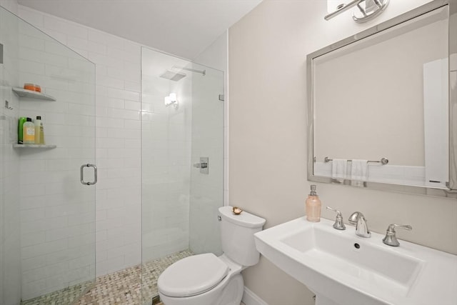 bathroom featuring sink, a shower with door, and toilet