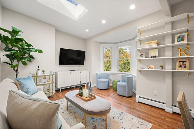 living room featuring hardwood / wood-style floors, a skylight, and a baseboard heating unit