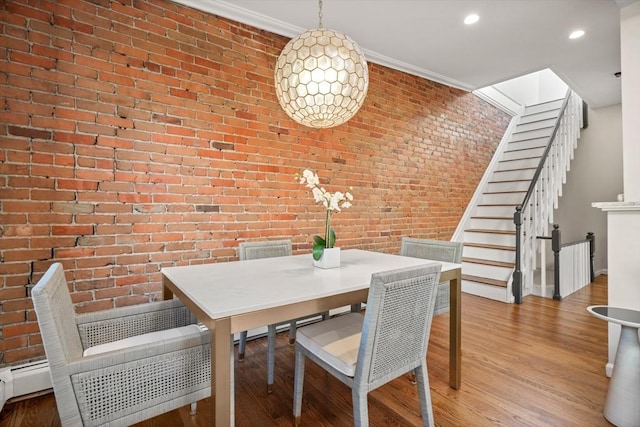 dining space featuring crown molding, brick wall, and light wood-type flooring