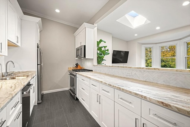 kitchen featuring white cabinetry, appliances with stainless steel finishes, sink, and light stone counters