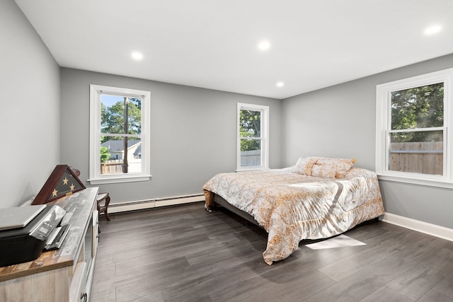 bedroom with a baseboard heating unit and dark hardwood / wood-style floors