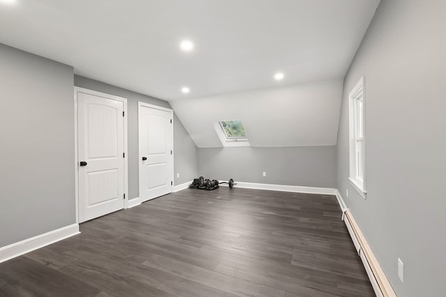 additional living space with baseboard heating, dark hardwood / wood-style flooring, and lofted ceiling with skylight