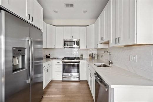 303 Maverick St Ph, Ph, Boston, MA 02128 - kitchen with light countertops, backsplash, appliances with stainless steel finishes, a sink, and wood finished floors