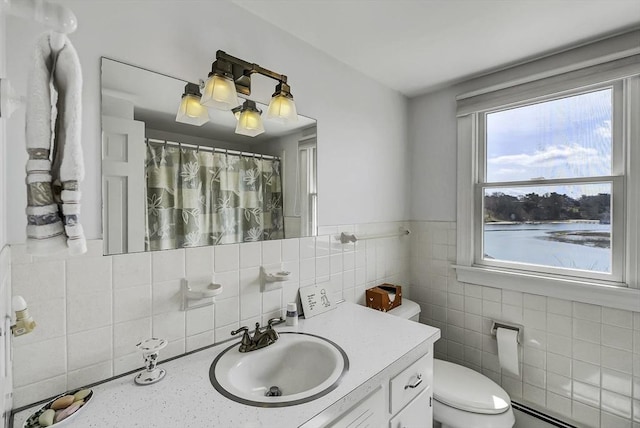 31 Baxendale Rd, Bourne, MA 02532 - full bath with tile walls, toilet, baseboard heating, vanity, and a wainscoted wall