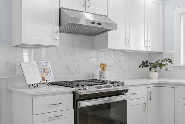 kitchen with under cabinet range hood, white cabinetry, tasteful backsplash, and gas range