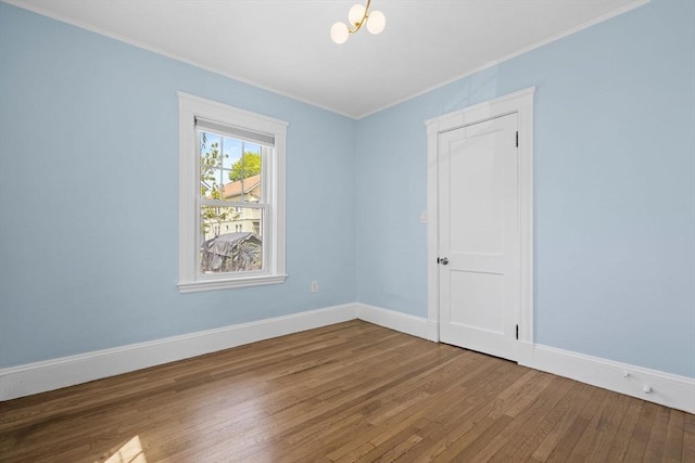 spare room featuring crown molding, baseboards, and wood finished floors