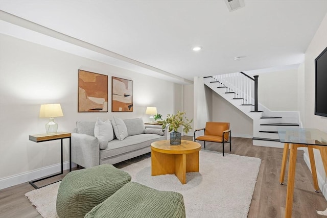 living area featuring visible vents, stairs, baseboards, and wood finished floors