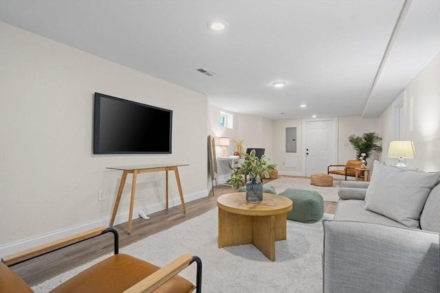 living room featuring visible vents, baseboards, recessed lighting, electric panel, and light wood finished floors