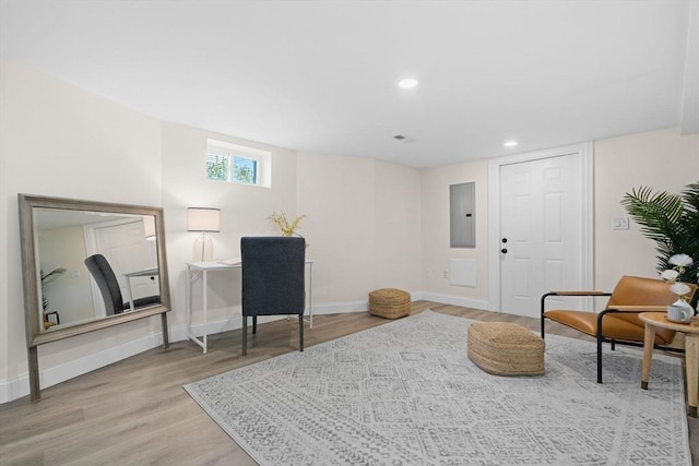 living area with baseboards, electric panel, recessed lighting, and wood finished floors