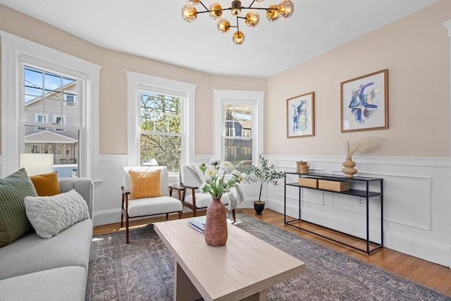 sitting room with wainscoting, a decorative wall, wood finished floors, and a chandelier