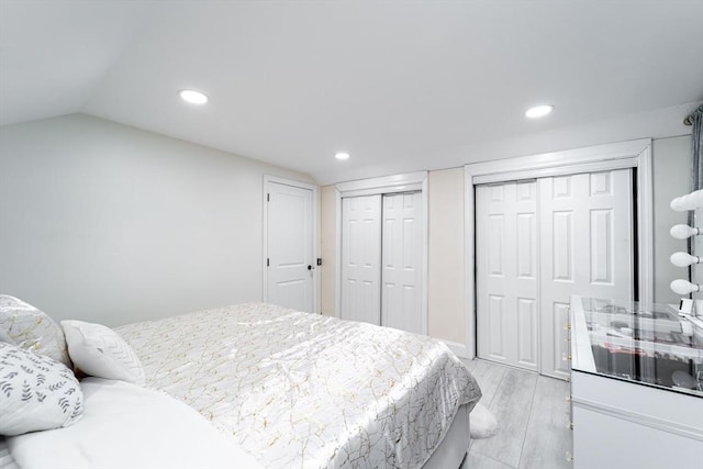 bedroom with light wood-style floors, two closets, and recessed lighting