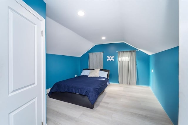 bedroom with vaulted ceiling, baseboard heating, wood finished floors, and recessed lighting