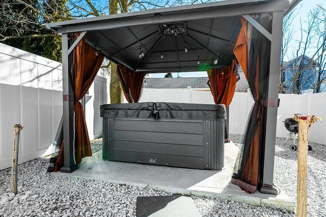 view of patio / terrace with a fenced backyard, a hot tub, and a gazebo