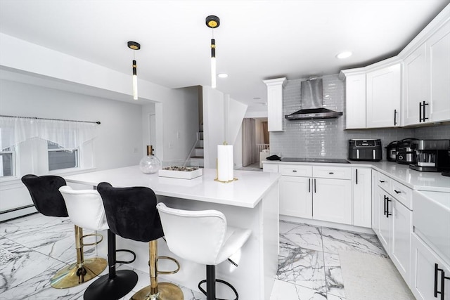 kitchen with a breakfast bar, marble finish floor, wall chimney exhaust hood, and tasteful backsplash