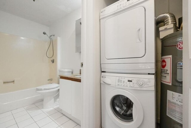 clothes washing area featuring stacked washing maching and dryer, water heater, and light tile patterned floors