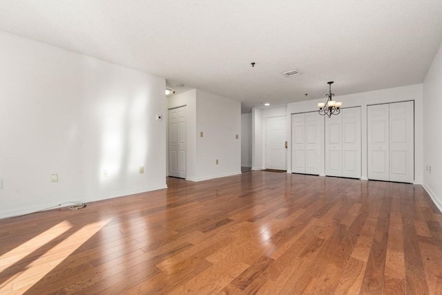 unfurnished living room featuring hardwood / wood-style floors and a notable chandelier