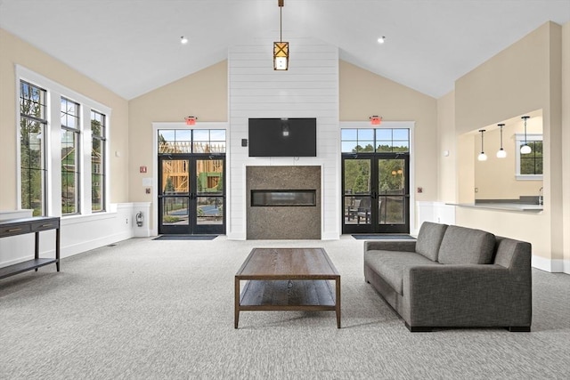 living area featuring a large fireplace, carpet, high vaulted ceiling, and baseboards