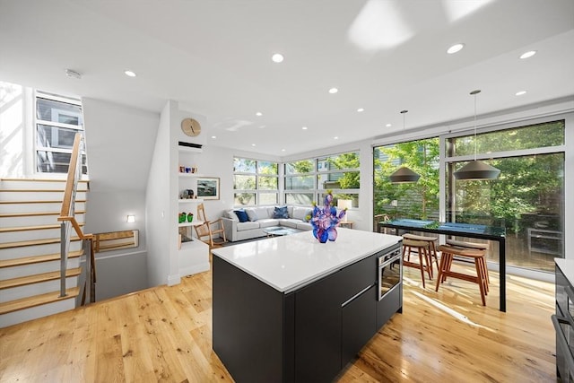 137 Walden St Unit 137, Cambridge, MA 02140 - kitchen with dark cabinetry, a kitchen island, recessed lighting, modern cabinets, and light wood-style floors