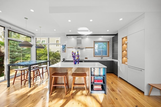 137 Walden St Unit 137, Cambridge, MA 02140 - kitchen featuring modern cabinets, wall chimney range hood, a kitchen island, a sink, and light countertops