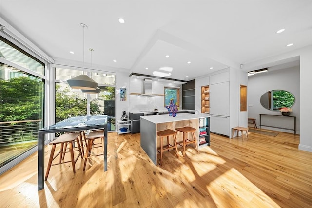 137 Walden St Unit 137, Cambridge, MA 02140 - kitchen featuring modern cabinets, light wood finished floors, light countertops, wall chimney exhaust hood, and pendant lighting