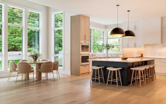 95 Blake St, Newton, MA 02460 - kitchen with stainless steel double oven, a breakfast bar, light wood-type flooring, light countertops, and a center island