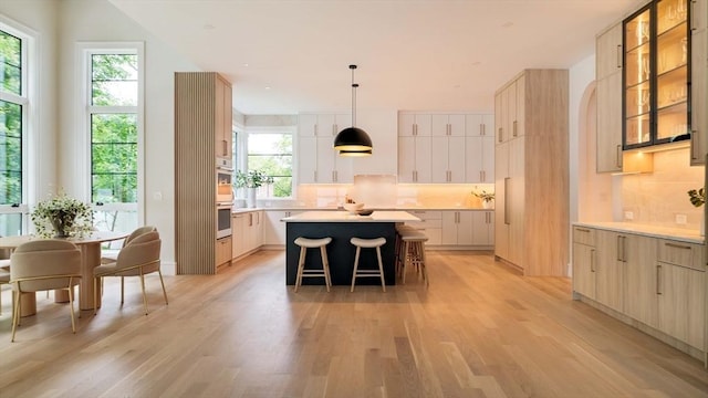95 Blake St, Newton, MA 02460 - kitchen with light wood-style floors, a center island, a breakfast bar area, tasteful backsplash, and modern cabinets