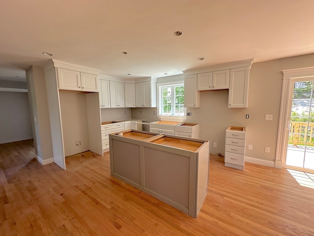 kitchen with white cabinets, a center island, and light hardwood / wood-style flooring