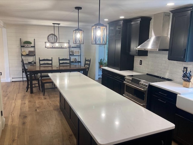 337 Mason Rd, Dudley, MA 01571 - kitchen with wall chimney exhaust hood, stainless steel range with electric cooktop, a large island, wood finished floors, and light countertops