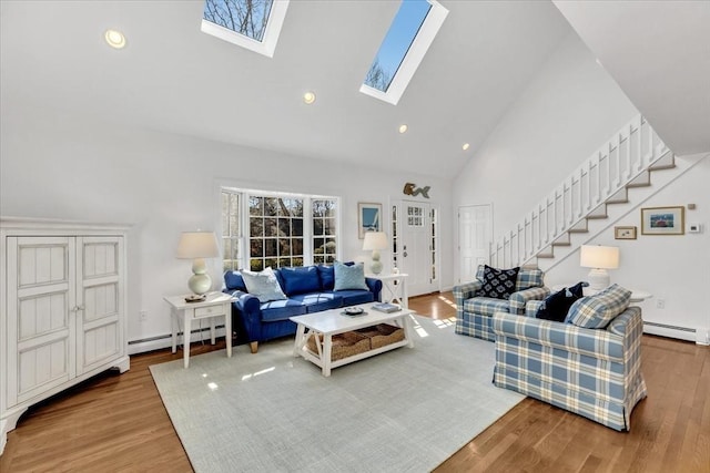 living room featuring stairway, wood finished floors, high vaulted ceiling, a baseboard radiator, and a skylight