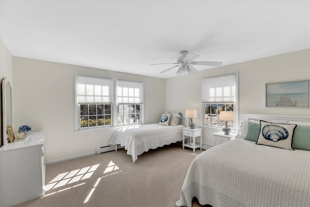 carpeted bedroom with a baseboard heating unit, multiple windows, a ceiling fan, and baseboards