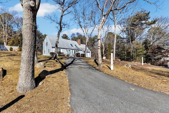 view of front of home featuring aphalt driveway, fence, and a chimney