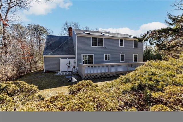 rear view of property featuring a chimney and a deck