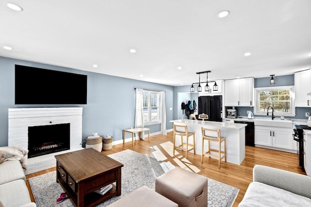 living area with a fireplace, recessed lighting, baseboards, and light wood-type flooring