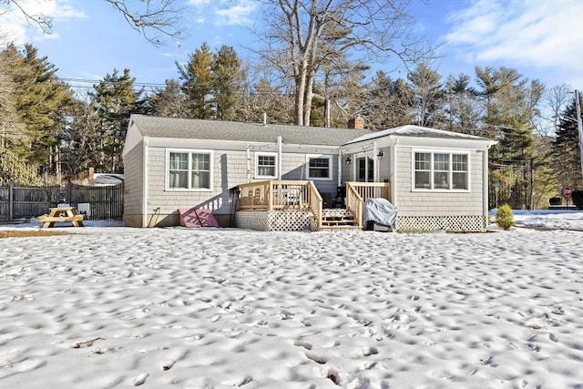 back of property with a deck, a chimney, and fence