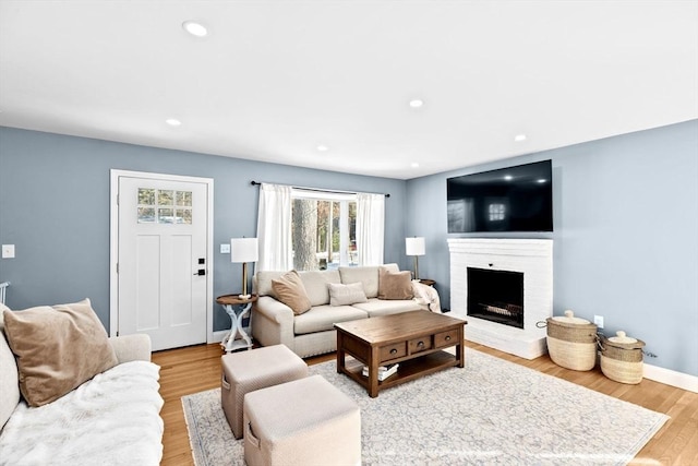 living room featuring light wood-style flooring, recessed lighting, a fireplace, and baseboards