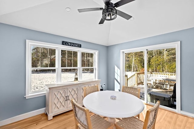 dining space with baseboards, light wood-style floors, a ceiling fan, and vaulted ceiling