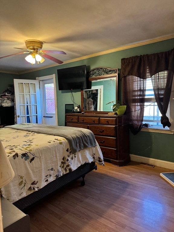 bedroom featuring multiple windows, ceiling fan, ornamental molding, and hardwood / wood-style flooring