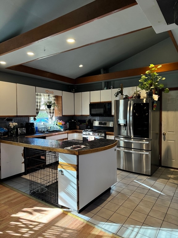 kitchen featuring decorative backsplash, stainless steel appliances, white cabinetry, and lofted ceiling