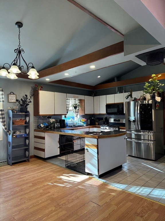 kitchen with white cabinetry, hanging light fixtures, an inviting chandelier, appliances with stainless steel finishes, and light wood-type flooring