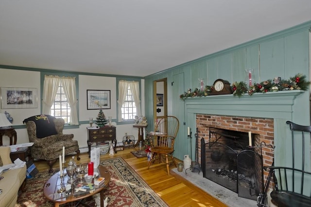 living room featuring crown molding, a brick fireplace, and wood-type flooring